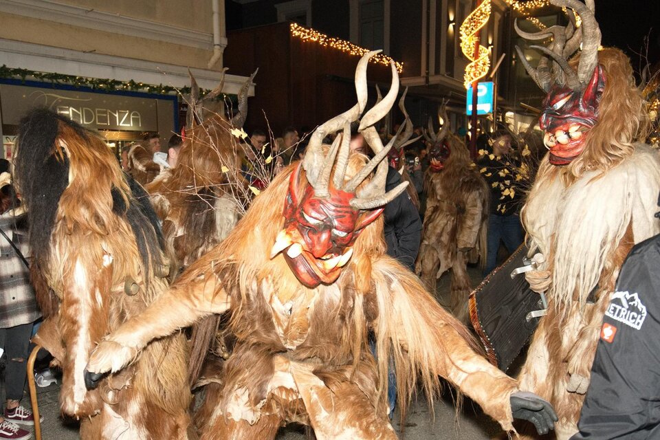 Eine festliche Parade mit maskierten Figuren, die beeindruckende Kostüme und Hörner tragen. Die Stimmung ist lebhaft und feierlich. | © Marco Stoica