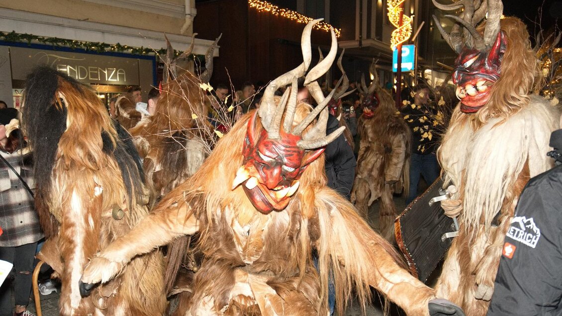 Eine festliche Parade mit maskierten Figuren, die beeindruckende Kostüme und Hörner tragen. Die Stimmung ist lebhaft und feierlich. | © Marco Stoica