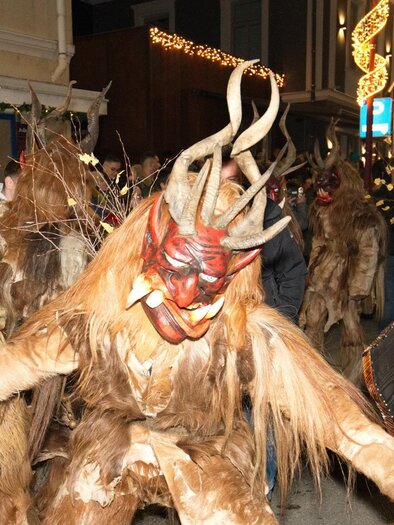 A festive parade with masked figures wearing impressive costumes and horns. The atmosphere is lively and festive. | © Marco Stoica
