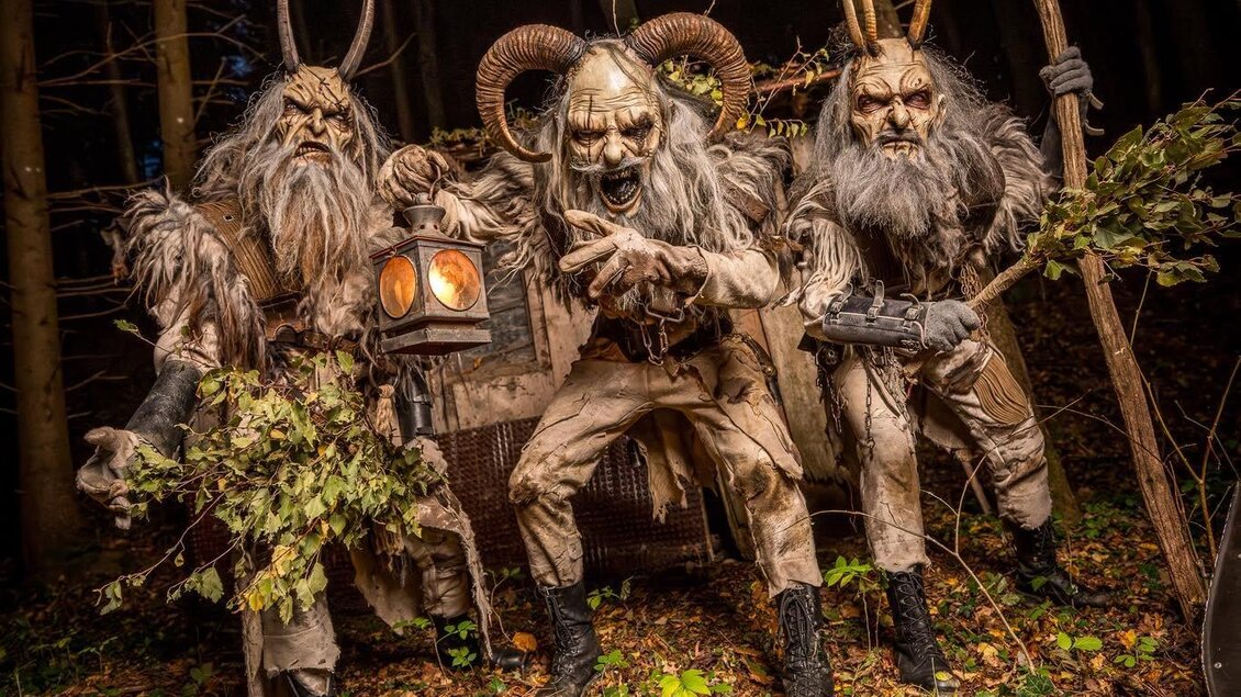 Drei eindrucksvoll verkleidete Krampusfiguren mit Hörnern, Masken und zotteligen Gewändern sorgen in einem nächtlichen Wald für eine schaurig-mystische Atmosphäre. Eine leuchtende Laterne, Äste und rustikale Requisiten unterstreichen die düstere Inszenierung. Zu sehen beim Krampuslauf Fürstenfeld.

 | © Laura Gimpel
