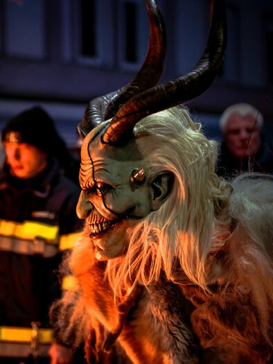Krampus with white fur, next to an official at the barrier. | © Fabian Anderle
