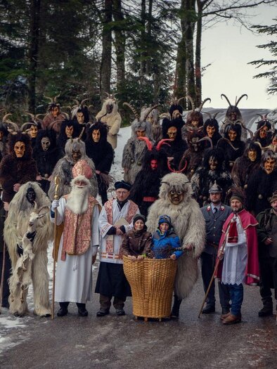 Gruppenbild der Nikologruppe Kumitz auf der Einfahrt zum Kumitzberg. In der ersten Reihe stehen die lichten Gesellen des Nikolaus, dahinter die dunklen Krampusse mit ihren unterschiedlichen Masken. | © Lebensbilder - Christine Struz