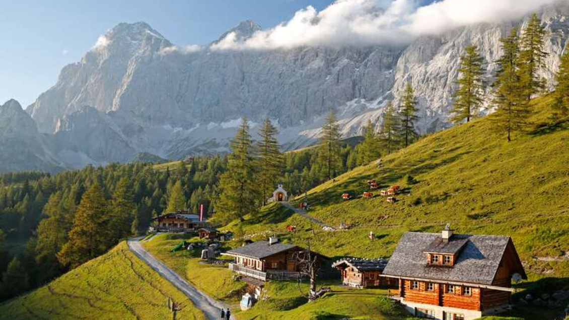 Eine malerische Berglandschaft mit Alm-Hütten und grünen Wiesen. Hohe Berge und ein klarer Himmel prägen die Szenerie. | © Herbert Raffalt