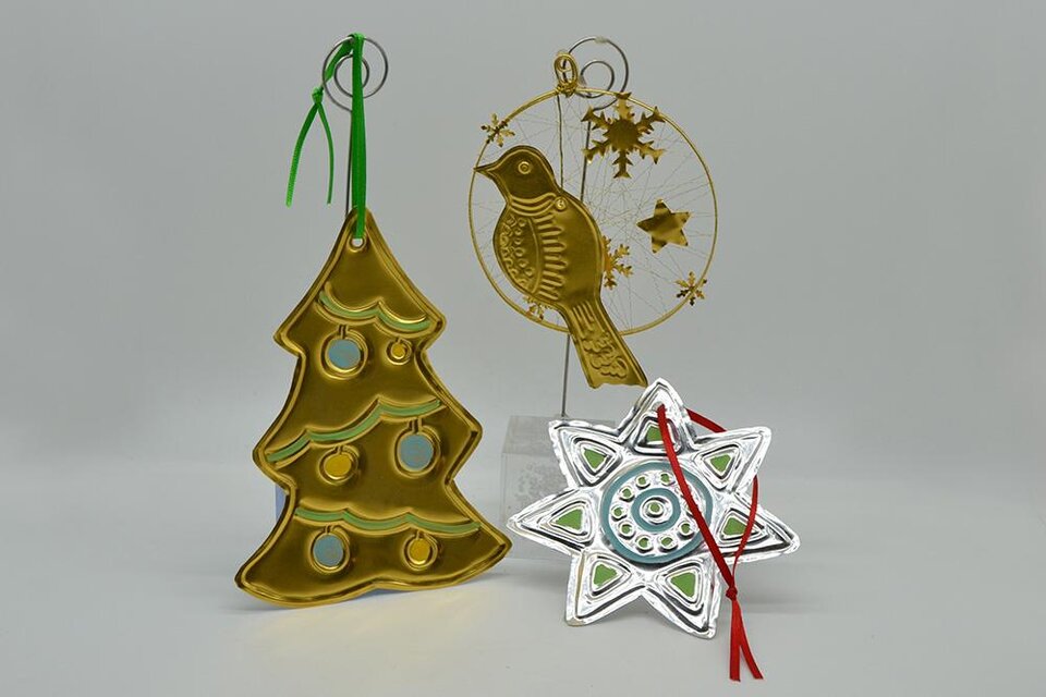 Drei dekorative Weihnachtshänger in Gold und Silber. Sie zeigen einen Weihnachtsbaum, einen Vogel und eine Schneeflocke. | ©  MuseumsCenter Leoben