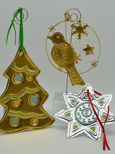 Three decorative Christmas ornaments in gold and silver. They feature a Christmas tree, a bird, and a snowflake. | ©  MuseumsCenter Leoben
