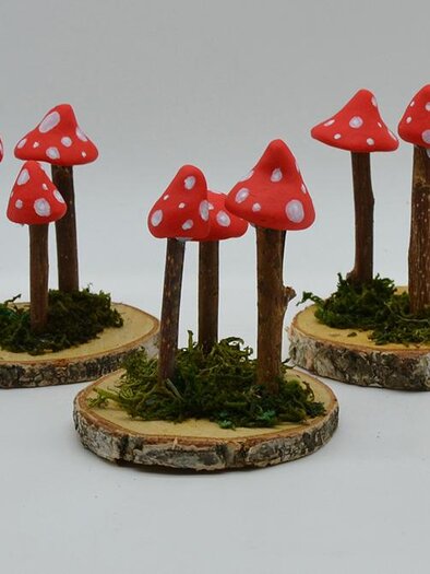 Vivid red mushrooms standing on small wooden slices. The mushrooms have white spots and are surrounded by green moss. | ©  MuseumsCenter Leoben