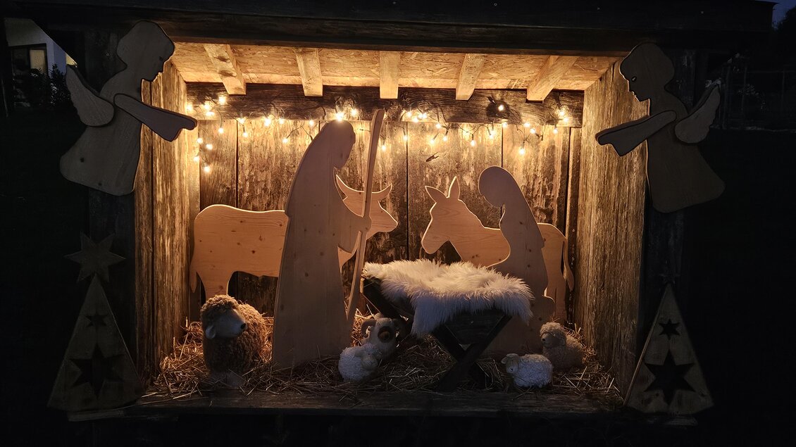 Eine beleuchtete Krippe mit Figuren von Maria, Josef und Tieren. Umgeben von dekorativen Engeln und Weihnachtslichtern. | © Marktgemeinde Halbenrain