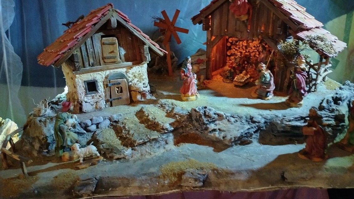 Ein Krippenspiel mit zwei Häusern und Figuren aus der Weihnachtsgeschichte. Im Hintergrund sind Engel und liebevolle Details zu sehen. | © KBM Otmar Wernhard