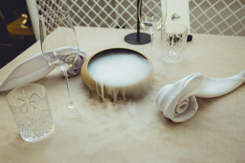 Gedeckter Tisch mit Gläsern und dampfendem Gericht bei Fine Dining in Graz. | © Pixelcoma-Cliff Kapatais