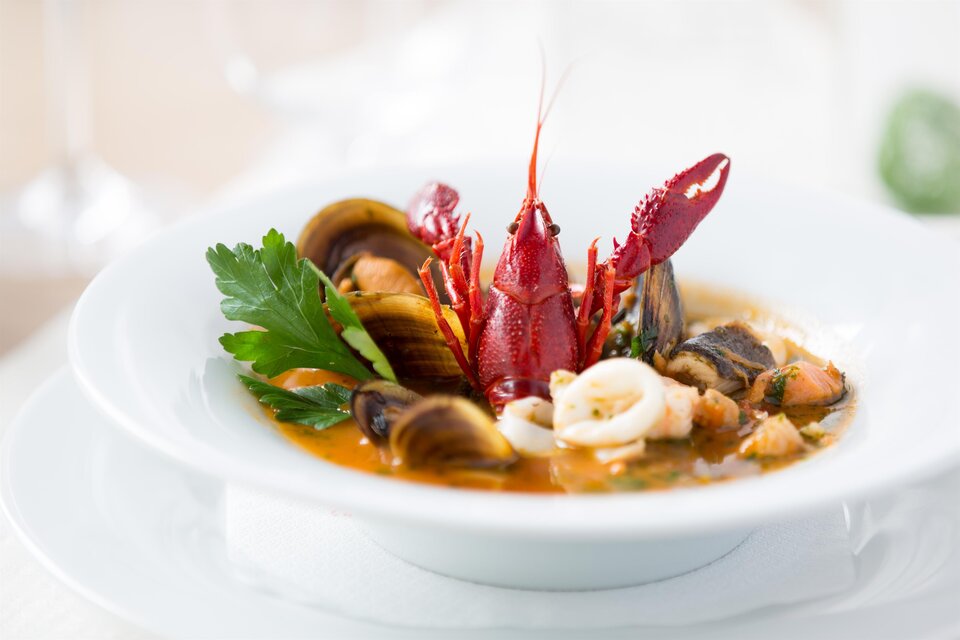 Teller mit Fischsuppe, Muscheln, Flusskrebs und Kräutern im Hügellandhof. | © Hügellandhof