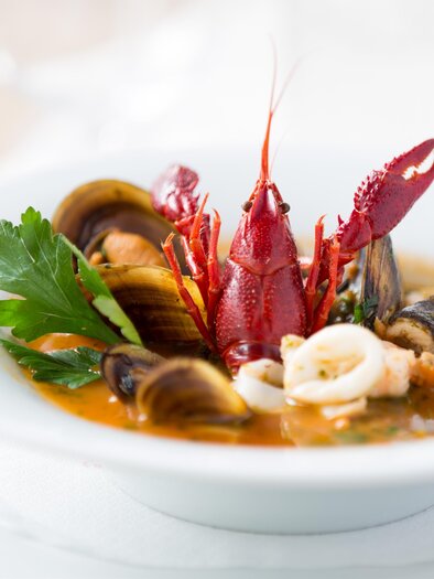 Teller mit Fischsuppe, Muscheln, Flusskrebs und Kräutern im Hügellandhof. | © Hügellandhof