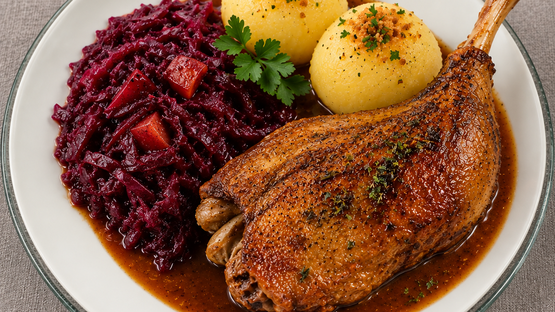 Knusprig gebratenes Martinigansl mit goldbrauner Haut, serviert mit herzhaftem Rotkraut, zwei Kartoffelknödeln und kräftiger Bratensauce auf einem weißen Teller. Traditioneller Herbstgenuss im Semriacherhof in Semriach. | © ChatGPT-Astrid Lackner
