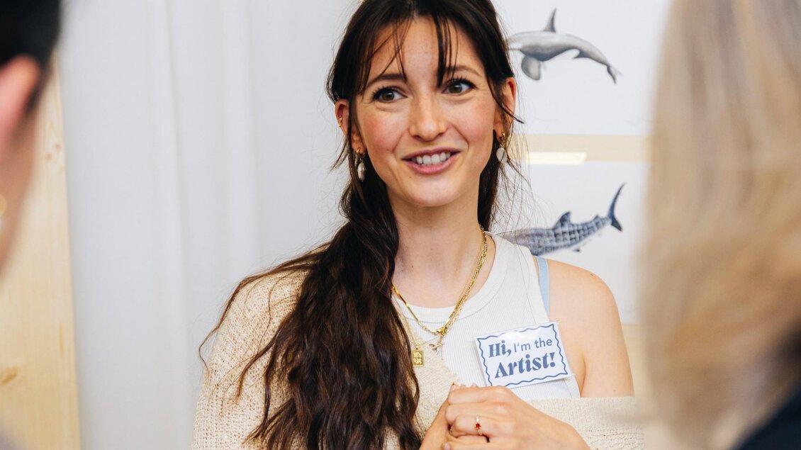 Eine Ausstellerin im Gespräch vor ausgestellten Tierillustrationen beim Kunst- und Designmarkt in Graz. | © Franziska Freiwald