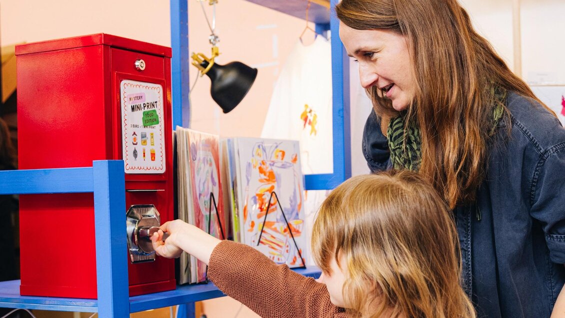 Ein Kind bedient im Beisein einer Frau einen Mini-Print-Automaten beim Kunst- und Designmarkt in Graz. | © Franziska Freiwald