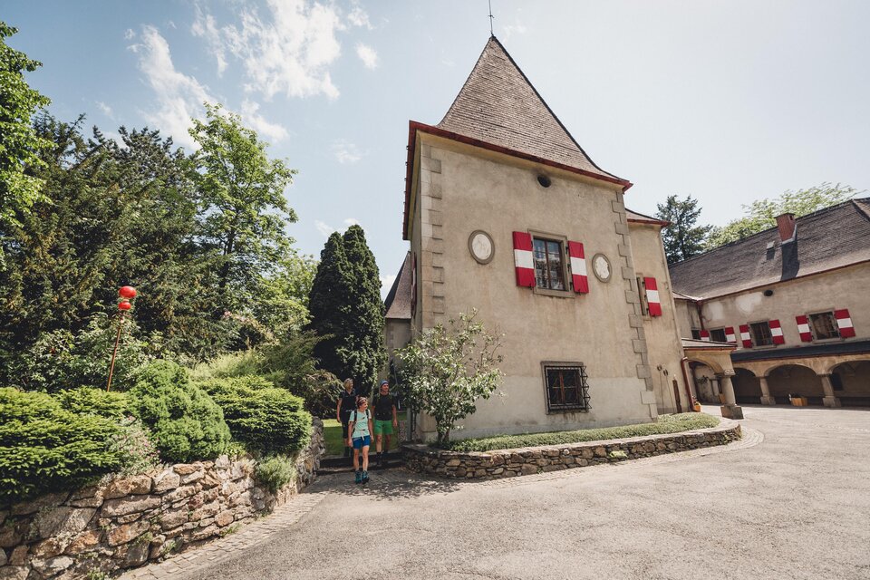 Ein historisches Gebäude mit einem spitzen Dach und roten Fenstern. Der umgebende Garten ist grün und gepflegt. | © TV Hochsteiermark, nicoleseiser.at