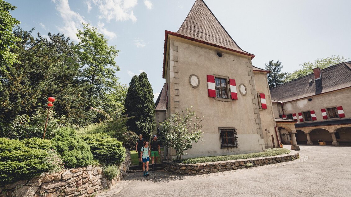 Ein historisches Gebäude mit einem spitzen Dach und roten Fenstern. Der umgebende Garten ist grün und gepflegt. | © TV Hochsteiermark, nicoleseiser.at