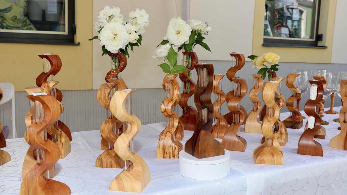 Eine Reihe von kunstvollen Holzskulpturen steht auf einem Tisch. Einige Vasen enthalten Blumen und zeigen die kreative Handwerkskunst. | © Stadtgemeinde Hartberg