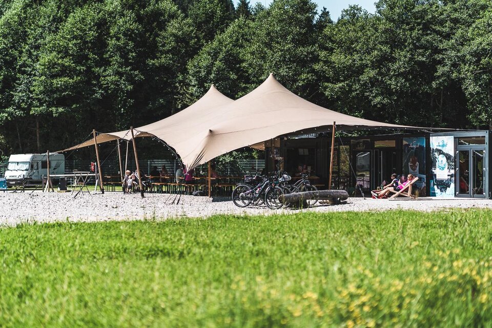 Ein gemütlicher Imbissstand mit großen roten Markisen. Holztische und Bänke laden zum Verweilen in schöner Natur ein. | © Auszeit Ausseerland