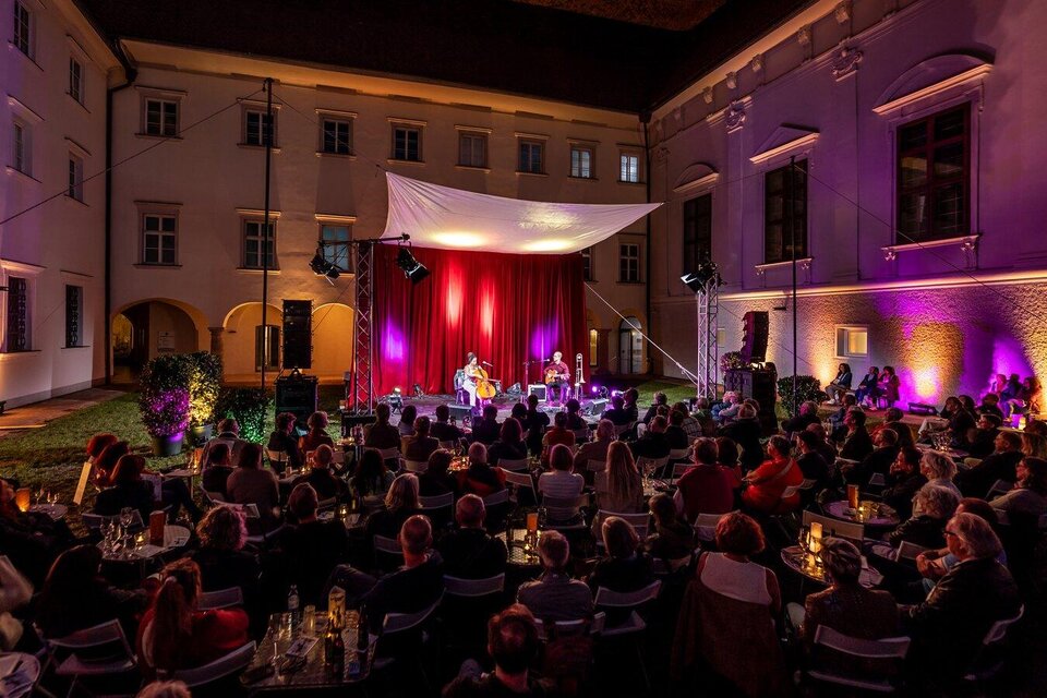 Ein Live-Auftritt im Freien mit einer großen Publikum. Bunte Lichter und eine festliche Atmosphäre unter einem Zelt. | © nikola-milatovic