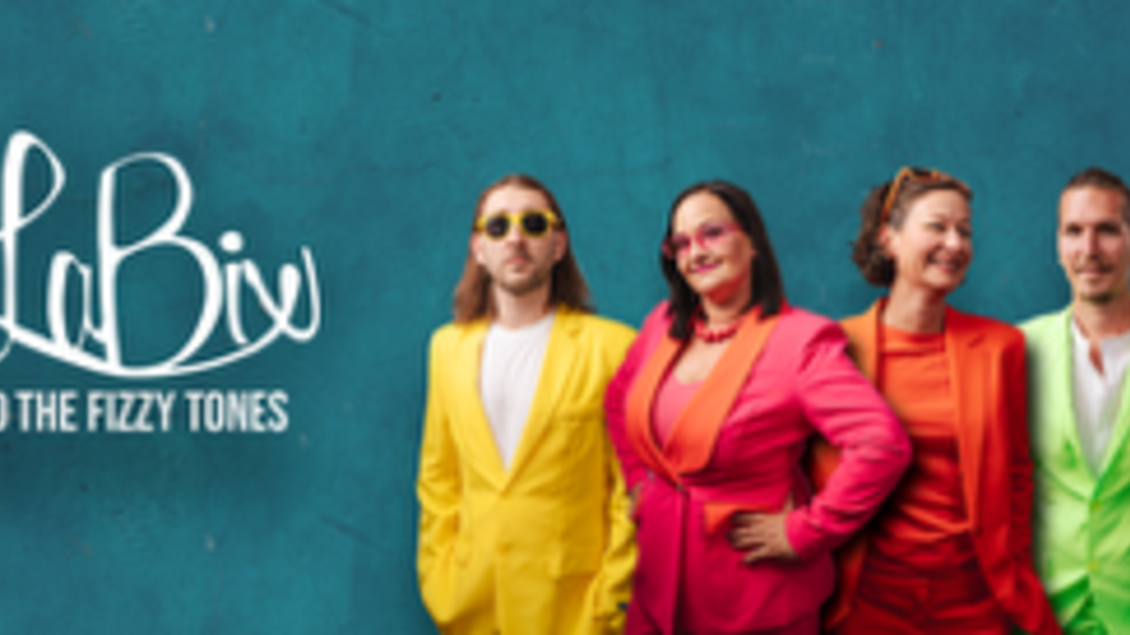 Eine Gruppe von vier Musikern posiert vor einer blauen Wand. Sie tragen auffällige, farbenfrohe Anzüge in Gelb, Pink, Orange und Grün. | © Plakat zur Veranstaltung