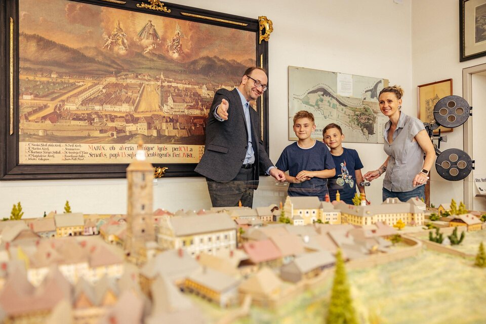 Eine Gruppe von Menschen steht um ein detailliertes Modell eines historischen Ortes. Im Hintergrund hängen Bilder und technische Geräte. | © Erlebnisregion Murtal