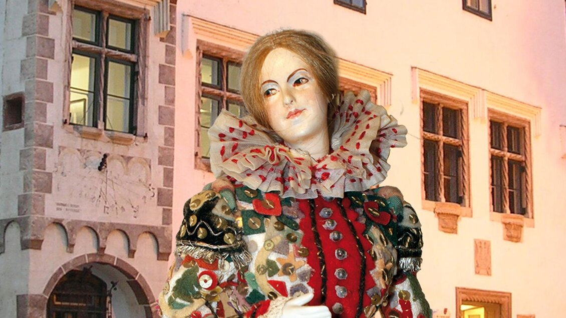 Eine kunstvolle Figur in historischer Kleidung vor einer alten Gebäudearchitektur. Die Details des Kostüms sind farbenfroh und opulent gestaltet. | © Kammerhofmuseum Bad Aussee