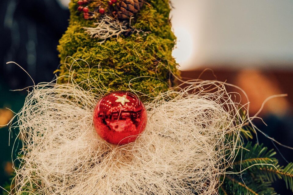 Ein dekorativer Weihnachtswichtel aus Moos mit einem roten Ornament und einem weißen Bart aus dekorativem Material. Der Hut des Wichtels verleiht ihm ein festliches Aussehen. | © MG Lannach - Petru Rimovetz