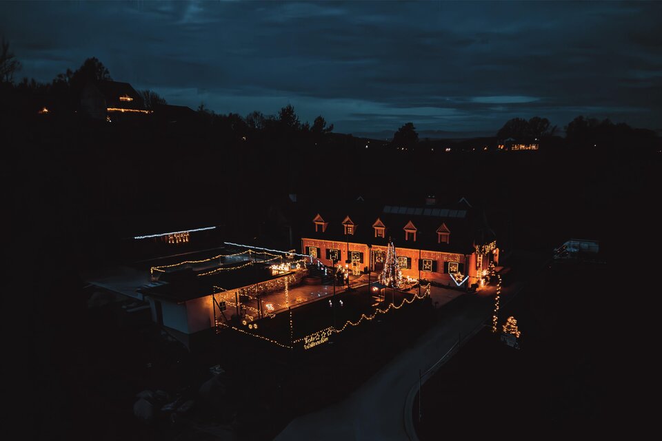 Ein festlich beleuchtetes Haus in der Dunkelheit. Die warme Beleuchtung schafft eine einladende Atmosphäre im Freien. | © Fam. Wimmer