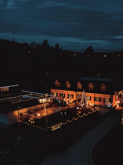 A festively illuminated house in the darkness. The warm lighting creates an inviting atmosphere outdoors. | © Fam. Wimmer