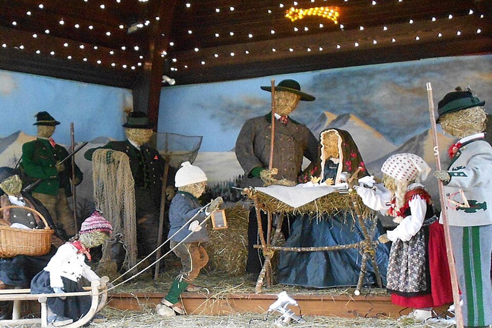 <p>Die lebensgroße Weihnachtskrippe im Musikpavillon im Gemeindepark von Grundlsee mit Figuren aus Stroh, die die heilige Familie darstellen. Die Szene zeigt auch traditionelle Handwerker und Bauern in festlicher Atmosphäre.</p> | © Hildegard Mittermair