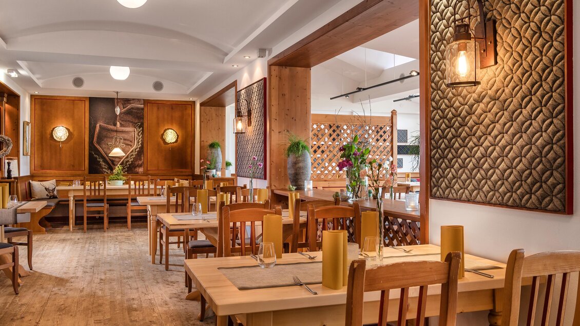 <p>Das gemütliche Restaurant mit Holzstühlen und Tischen beim Mondi Hotel Grundlsee. Die Wände sind dekorativ mit Texturen und Pflanzen geschmückt.</p> | © www.grundlsee.mondihotels.com