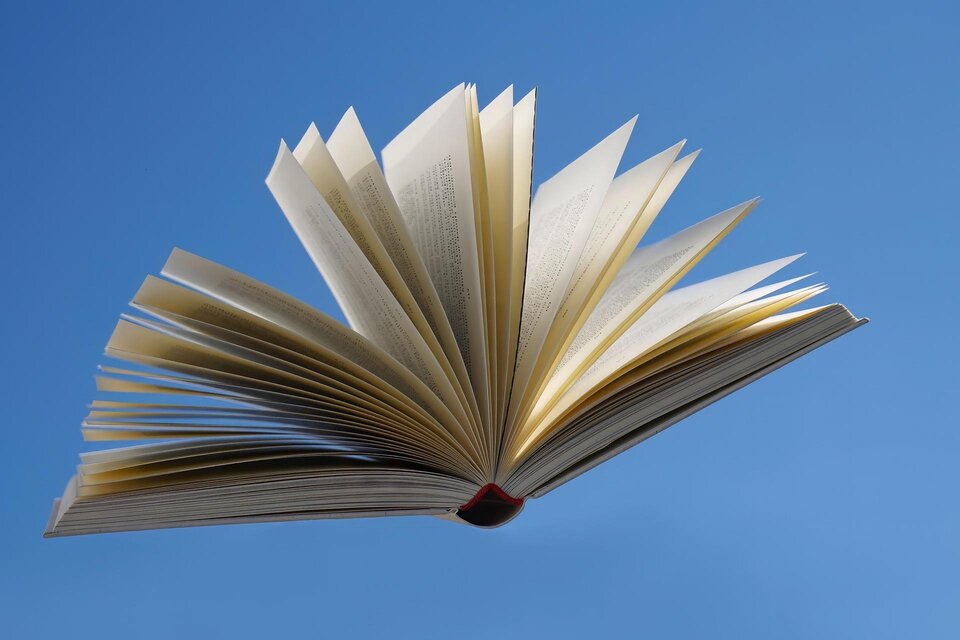 Ein aufgeschlagenes Buch schwebt vor einem klaren blauen Himmel. Die Seiten sind gut sichtbar und zeigen eine dynamische Anordnung. | © Pixabay