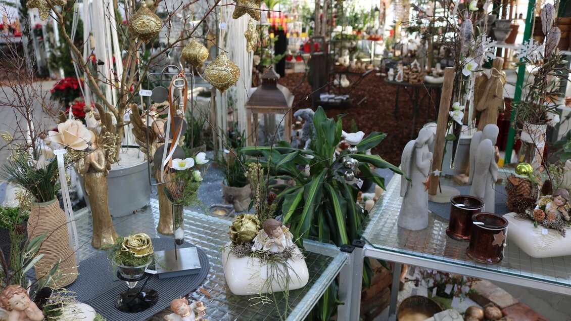 Ein dekorierter Verkaufsbereich mit verschiedenen Pflanzen und festlichen Ornamenten. Auf den Tischen sind Kerzen, Figuren und dekorative Elemente zu sehen. | © Blumen Kickenweiz