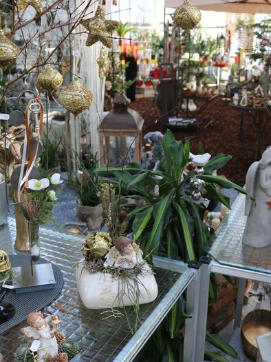 A decorated sales area with various plants and festive ornaments. On the tables, candles, figures, and decorative elements can be seen. | © Blumen Kickenweiz
