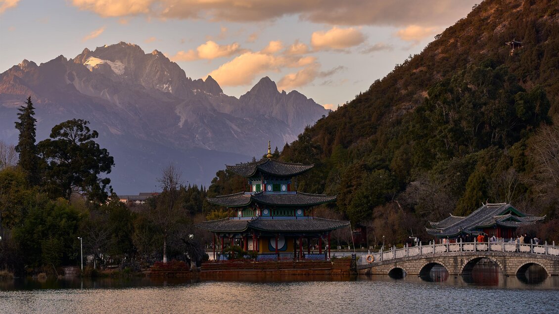 Eine Aussicht auf einen malerischen Tempel am Wasser, umgeben von Bergen und Bäumen. Der Himmel ist bei Sonnenuntergang in warmen Farben beleuchtet. | © Michael Fischer
