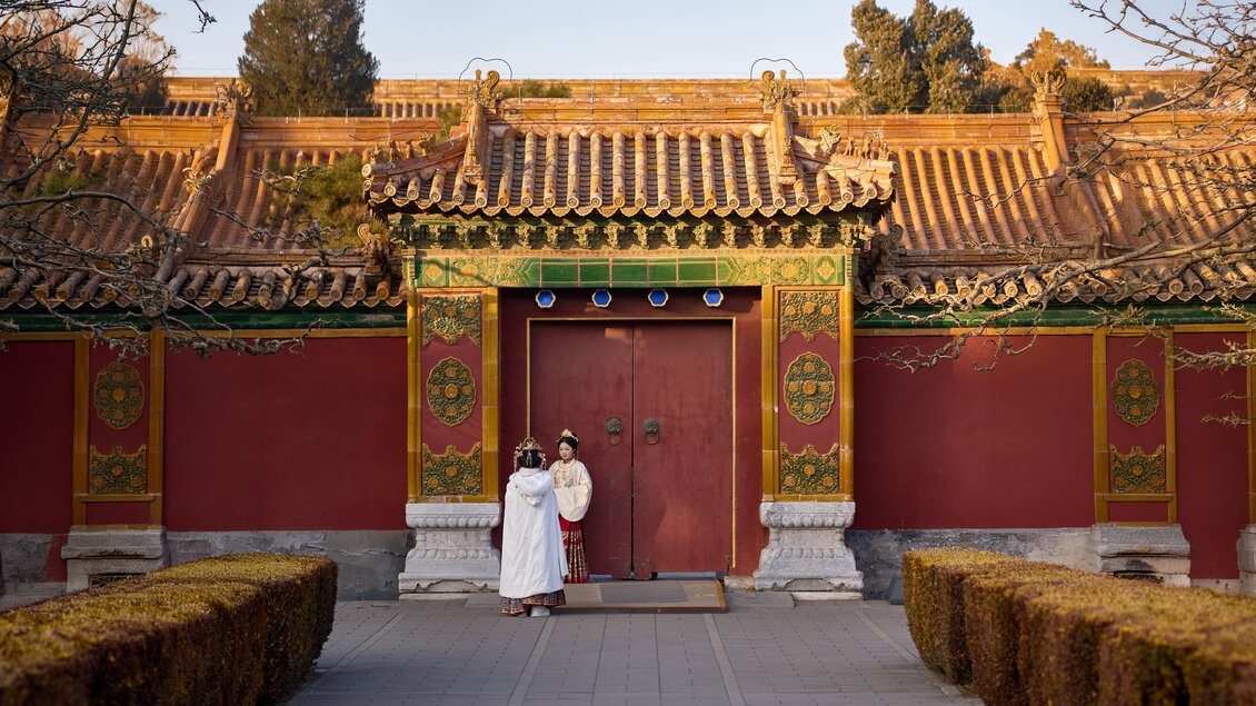 Ein traditionelles chinesisches Gebäude mit rote Wände und einem geschmückten Dach. Zwei Personen stehen vor einer großen, roten Tür. | © Michael Fischer