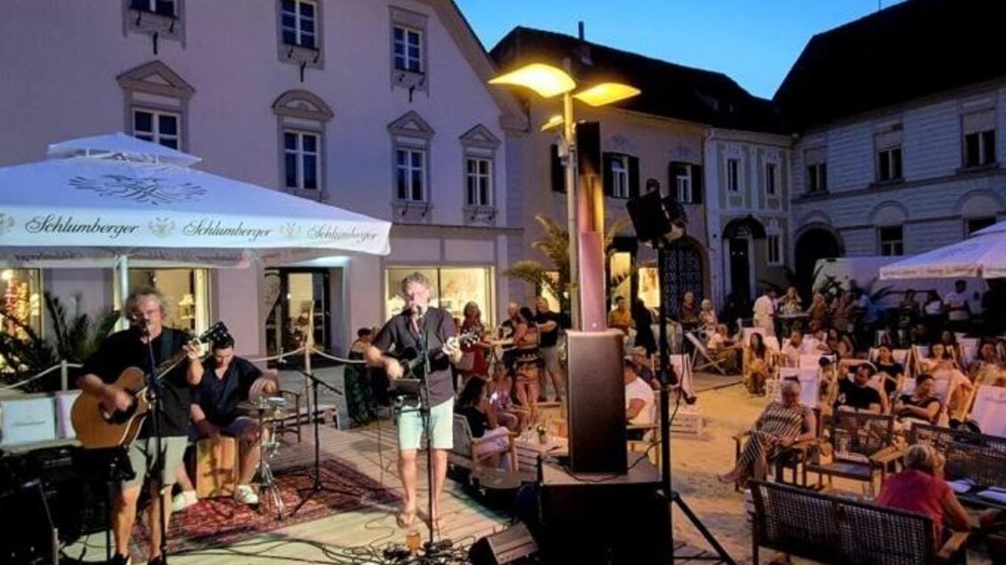 Eine Band namens "zeitlos" steht zusammen in formellen Schwarzhemden. Die Frau in der Mitte trägt ein rotes Kleid und lächelt, während die anderen Bandmitglieder freundlich posieren. | © Oststeiermark Tourismus