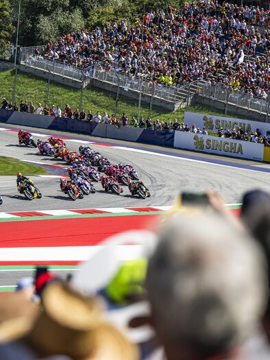 An exciting motorcycle race on a racetrack with cheering spectators. The riders are taking a turn at high speed. | © Lucas Pripfl - Red Bull Ring