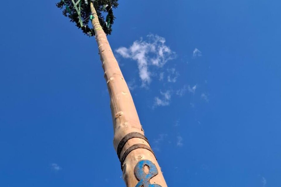 Ein hoher Pfahl mit einem geflochtenen Kranz oben und einem dekorativen Symbol an der Seite. Der Himmel ist blau mit ein paar weißen Wolken. | © Musikverein Bretstein