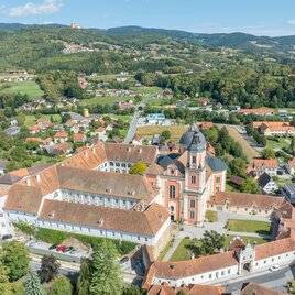 An impressive view of a monastery surrounded by green hills and rural landscape. The sky is blue and clear. | © Helmut Schweighofer