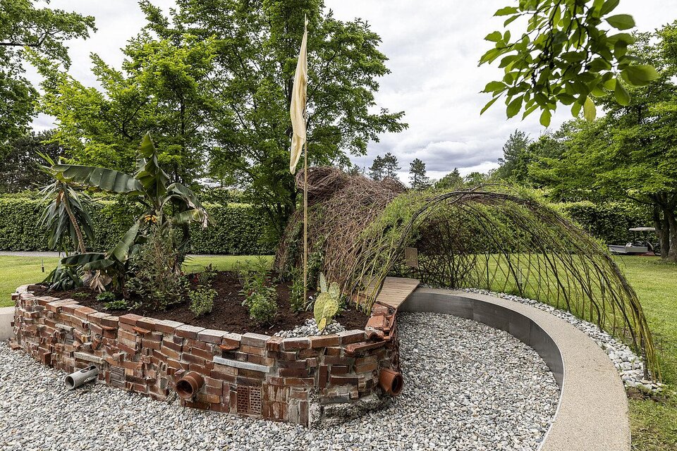 Ein kreativer Garten mit einer einzigartigen Struktur aus Ästen und Steinen. Im Hintergrund sind grüne Pflanzen und Bäume sichtbar. | © nikola-milatovic