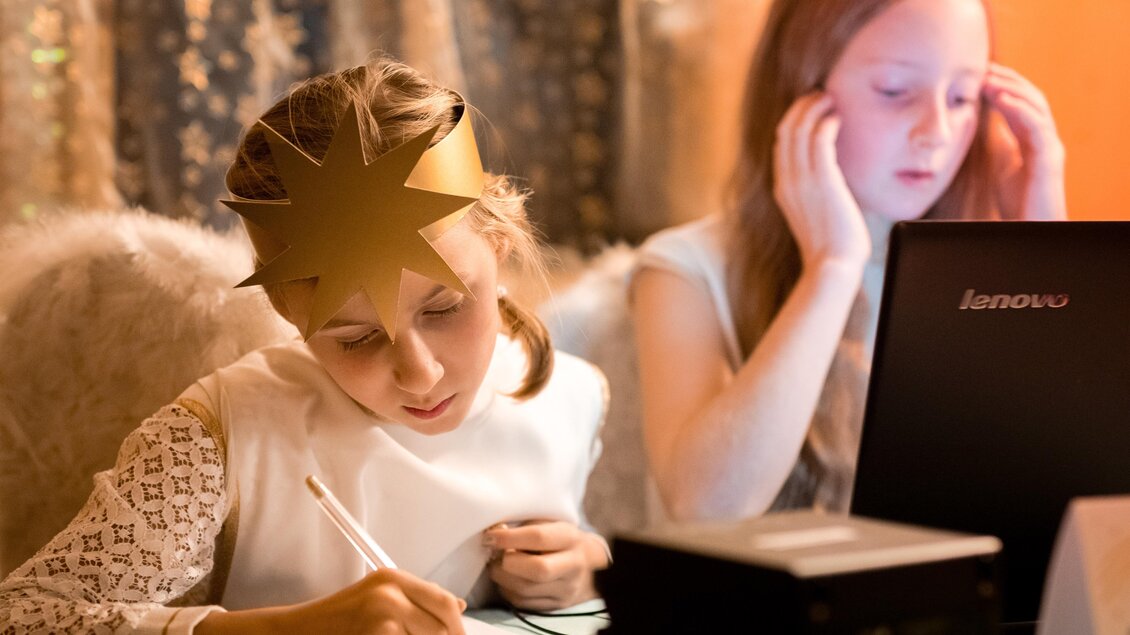 Zwei Mädchen sitzen in einem gemütlichen Raum. Eines der Mädchen schreibt mit einem Stift, während das andere am Laptop arbeitet. | © TV Hochsteiermark