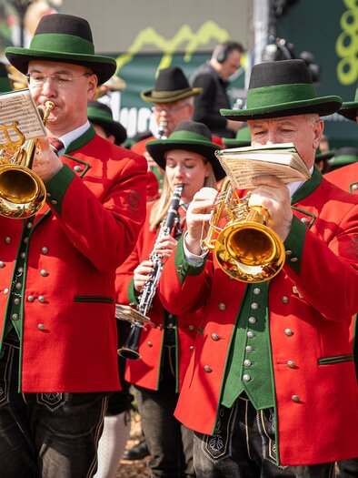 Eine Gruppe von Musikern trägt rote Jacken und schwarze Hüte. Sie spielen traditionelle Instrumente bei einem Festumzug. | © Ekatarina Paller