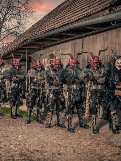 Krampusse mit rotem Gesicht und Hörnern vor einer alten Bretterbude! | © Seiersberger Höllbuam