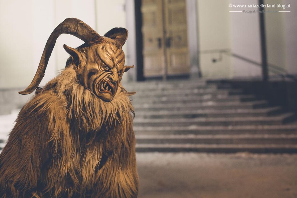 Eine gruselige Figur mit Hörnern steht vor einer Treppe. Der Charakter hat ein zotteliges Fell und eine bedrohliche Miene. | © www.mariazell.blog