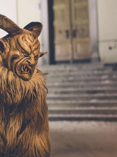 Eine gruselige Figur mit Hörnern steht vor einer Treppe. Der Charakter hat ein zotteliges Fell und eine bedrohliche Miene. | © www.mariazell.blog