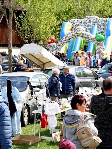 Ein belebter Flohmarkt mit vielen Ständen und Menschen. Im Hintergrund ist eine Hüpfburg zu sehen, die für Kinder steht. | © Kirchmeier