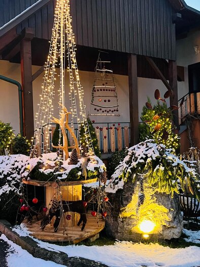 A festively decorated courtyard with snow-covered plants. String lights and Christmas decorations create a cheerful atmosphere. | © Wirtshaus Meißl