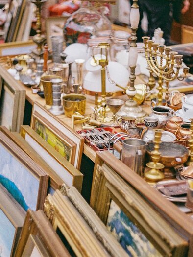 Ein bunter Flohmarkt mit vielen antiken Gegenständen und Bildern. Das Sortiment umfasst Lampen, Keramiken und Bilderrahmen.