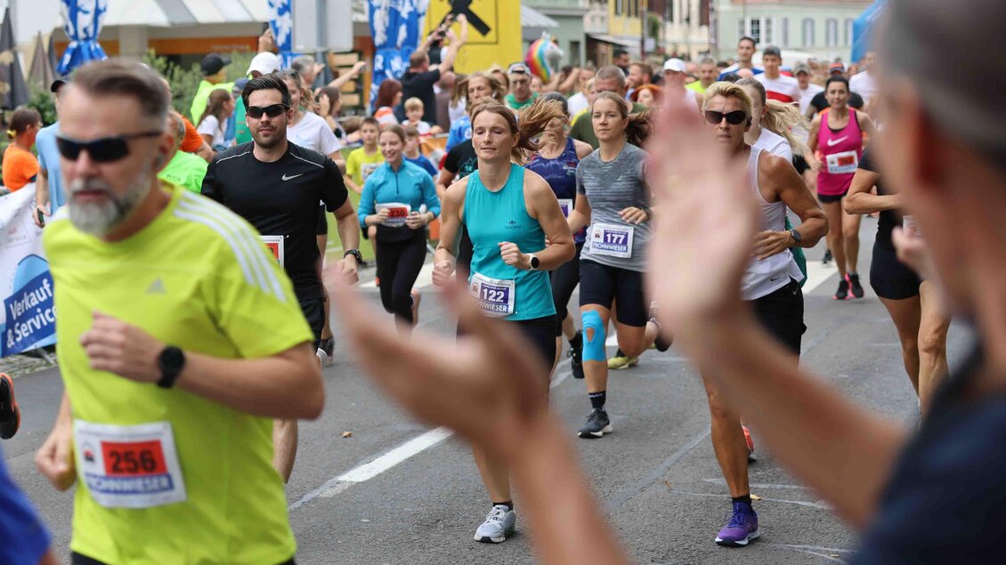 Ein Stadtlauf mit vielen Teilnehmern in sportlicher Kleidung. Zuschauer klatschen an der Strecke, während die Läufer vorbeiziehen. | © Murecker Aulauf